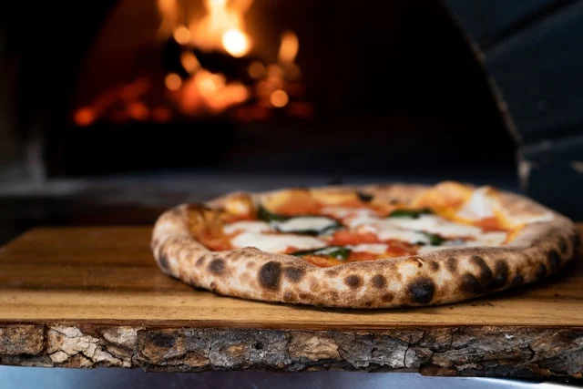 Pizza margherita in primo piano davanti al forno acceso